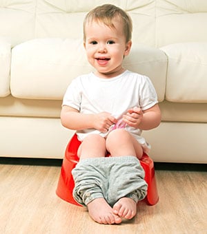 baby sitting on a potty chair with his pants down