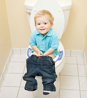 baby sitting on a potty seat with his pants down