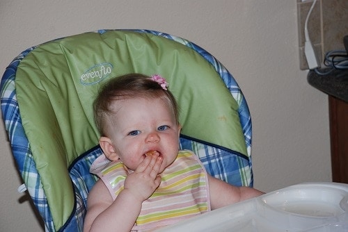 Baby sitting in blue and green highchair