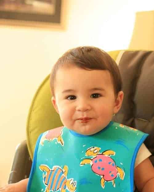 baby sitting wearing blue bib