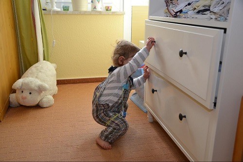 baby wearing jumper tried to open drawer