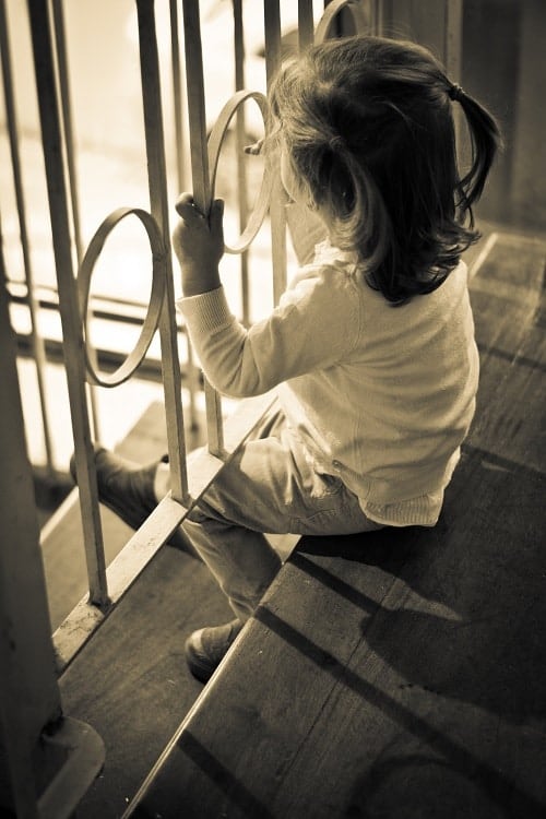 toddler sitting in stair with cage