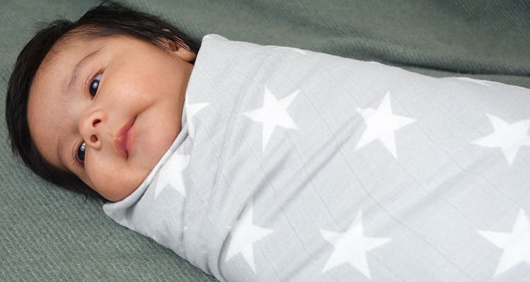 Baby boy wrapped in aden and anais swaddle blanket