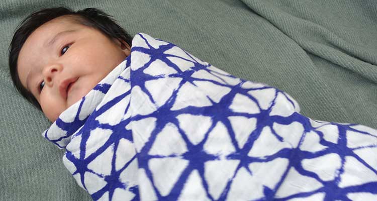 Baby boy wrapped in silky soft muslin aden and anais swaddle blanket