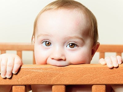 baby chewing on crib rail - best cribs