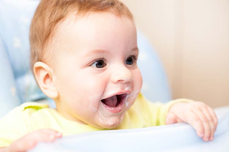 Baby wearing yogurt all over face and mouth