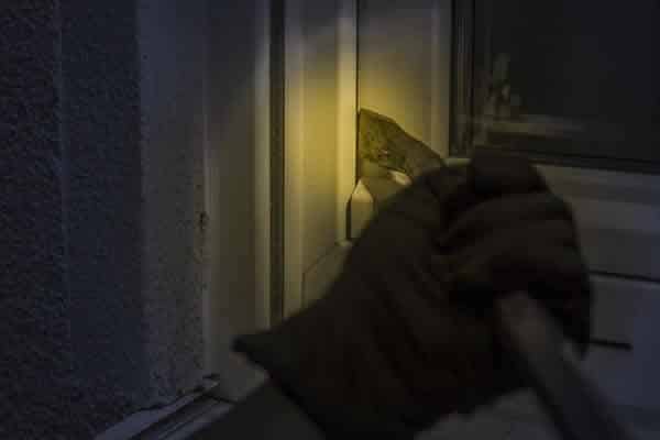 Burglar trying to open window at night using crowbar