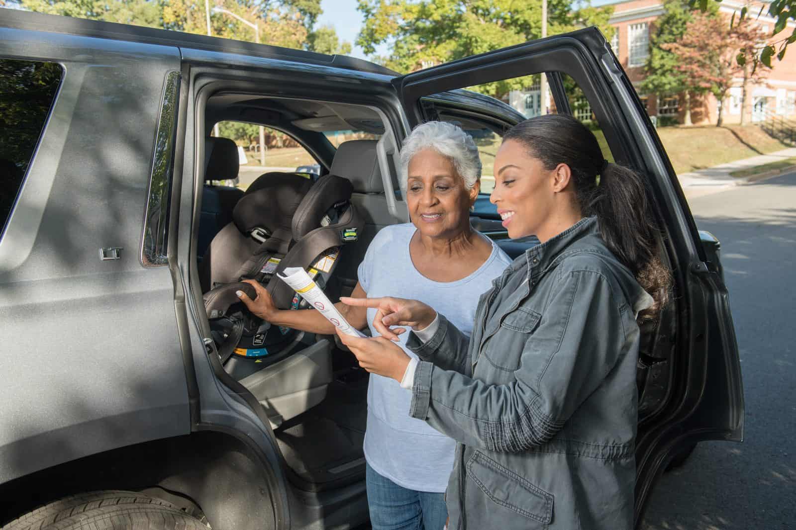 Two adults talking about a rear facing seat in the car.