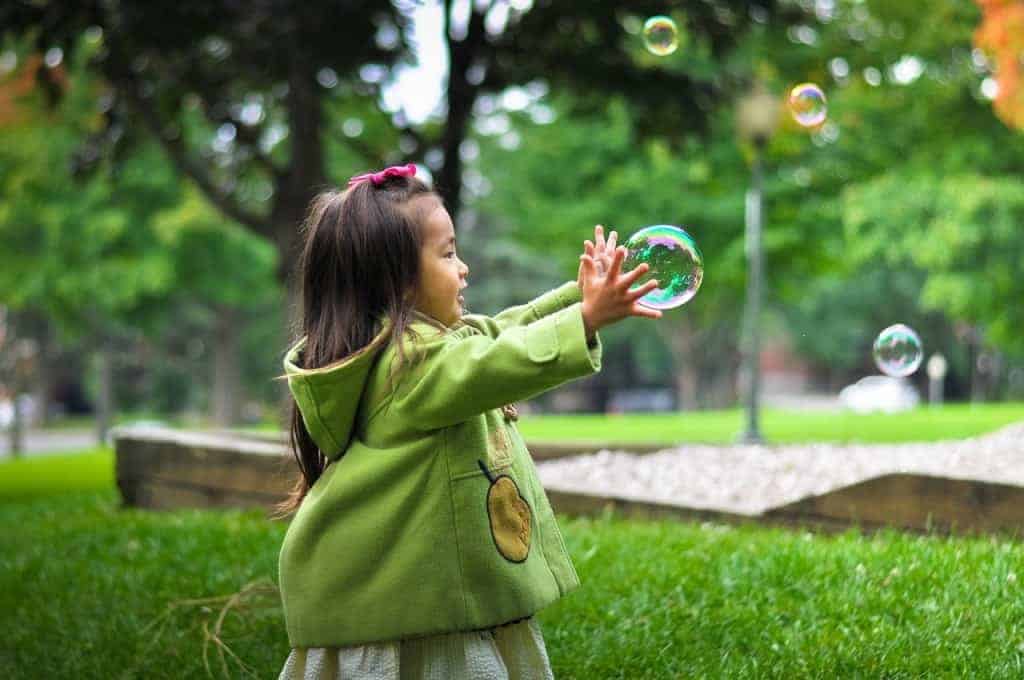 Girl playing on bubbles outdoors