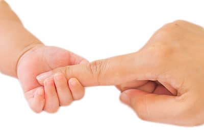 tiny baby hand wrapped around mothers index finger