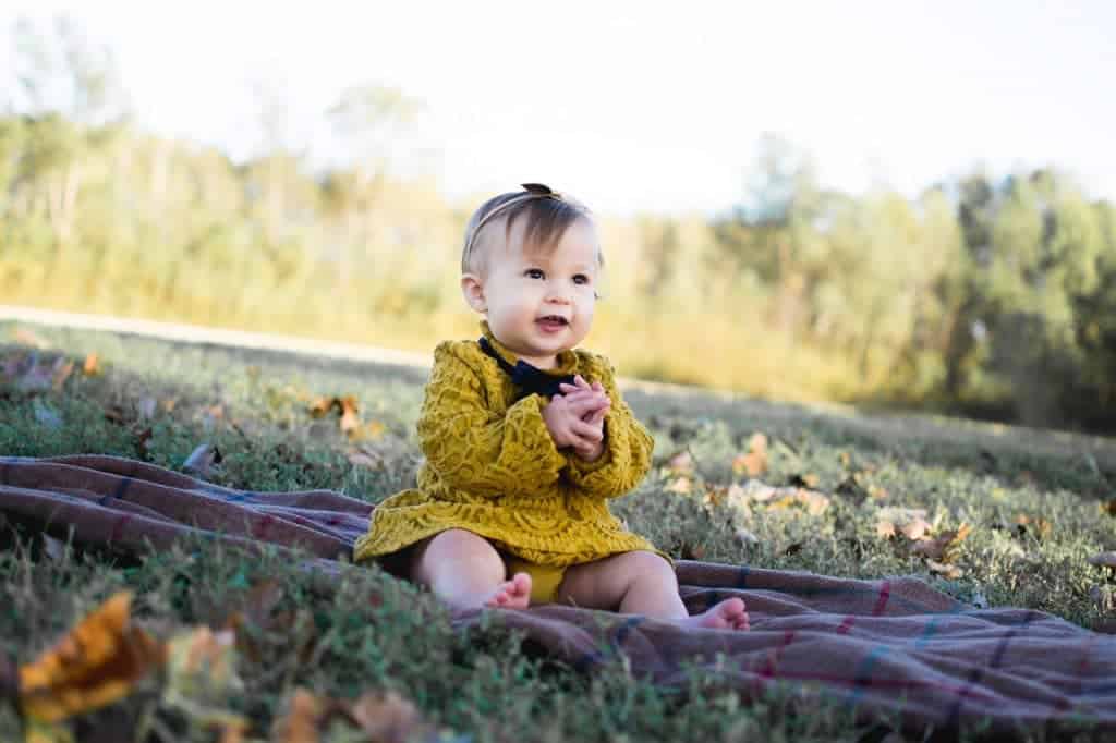 baby girl sitting on blanket outdoors