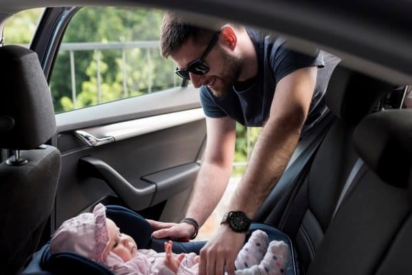 man taking baby out childish. safety seat