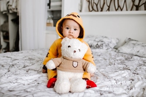 toddler sitting on bed beside white bear