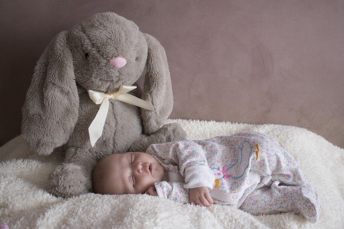 baby sleeping beside teddy bear