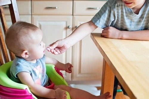 baby sitting at the green and purple highchair