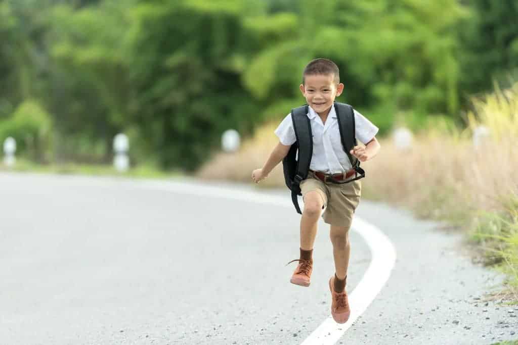 Running Little Boy wearing a school uniform and the best kids backpacks