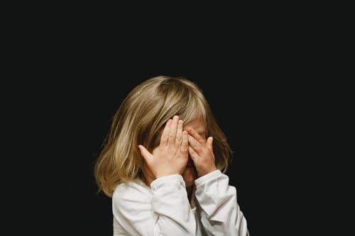 girl cover her face with both hands