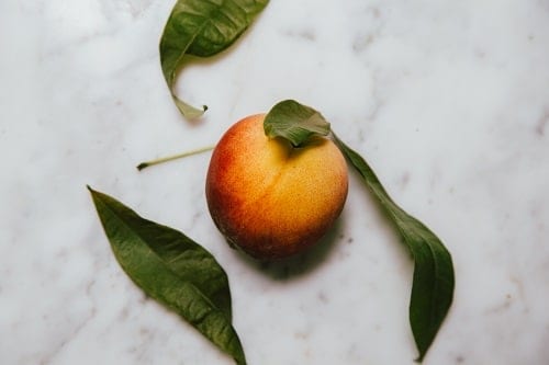red peach with green leaves