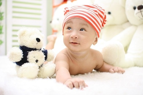 Smilling baby beside stuff toys