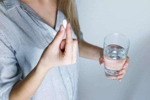 woman takes her folic acid supplement