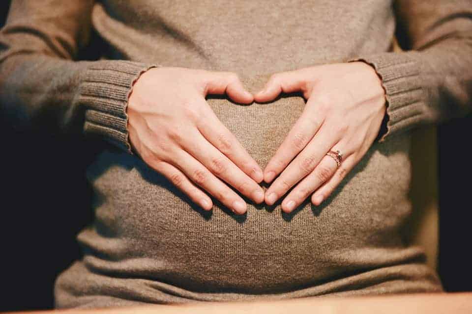 pregnant woman forming heart shape with her hands