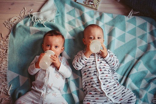 two babies lying on teal textile