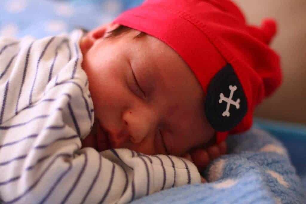 A sleeping baby in a red hat with a pirate patch