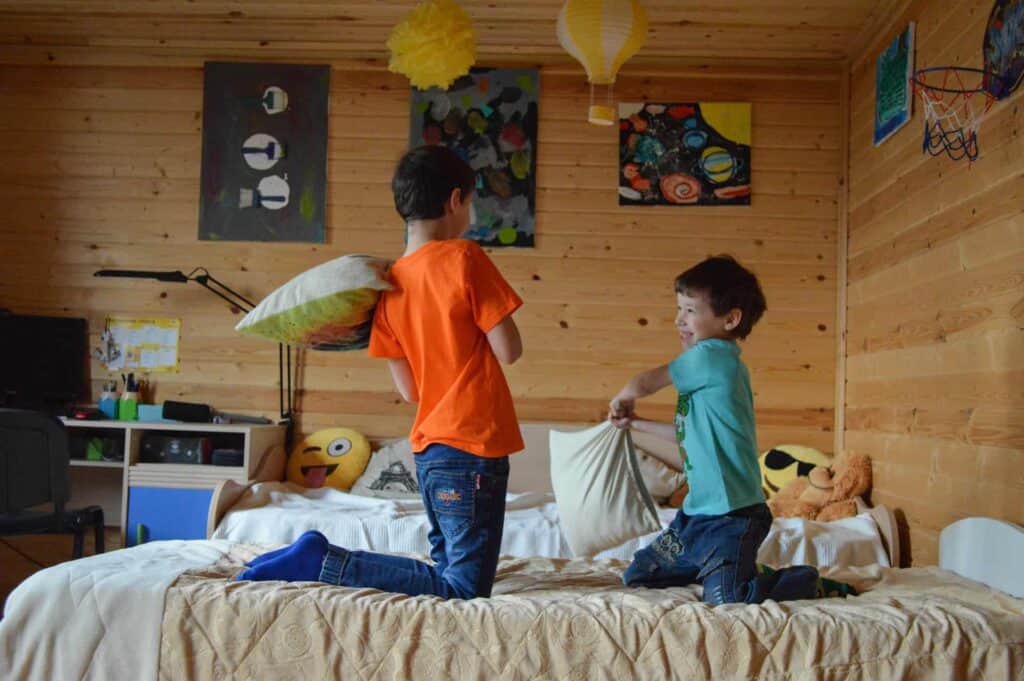 Two boys with cabin fever have a pillow fight on their bed