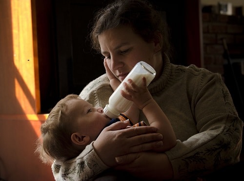 mother and son with bottle formula full of mlik