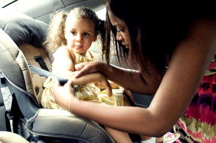 A mom buckles her child into a car seat