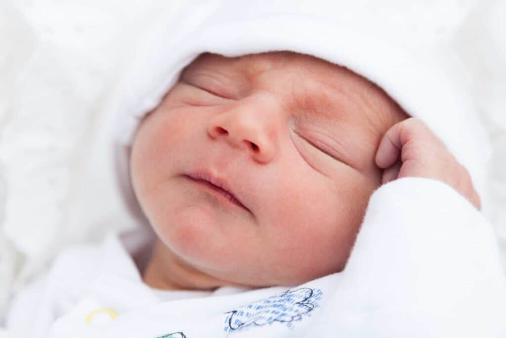 Sleeping baby that needs its nose cleared with a nasal aspirator