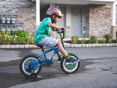 boy practicing bike with training wheels