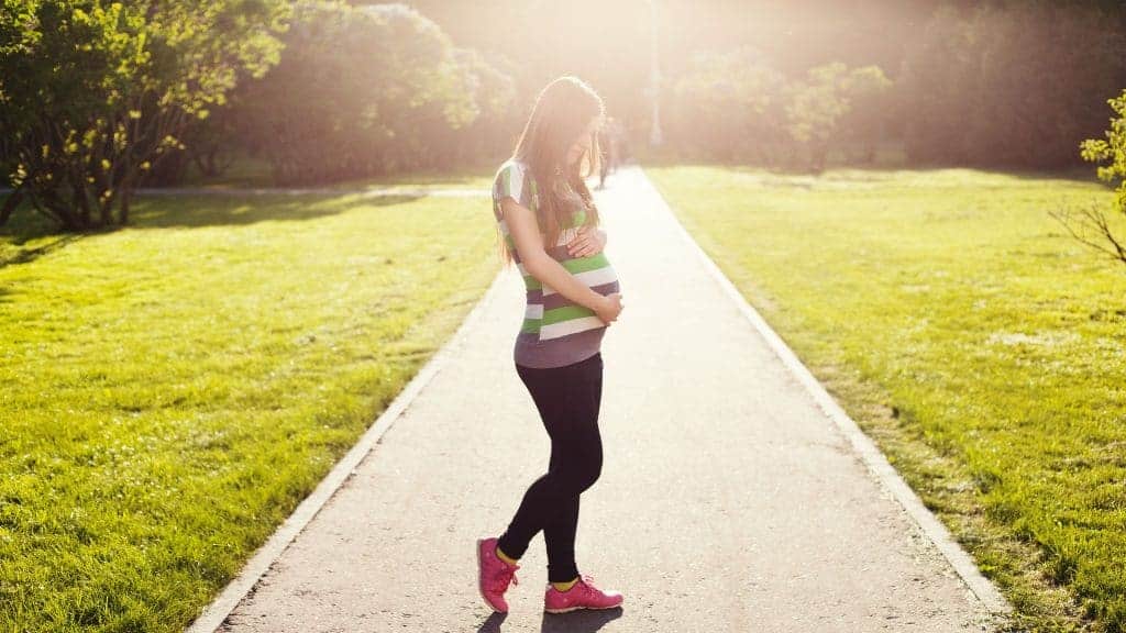 Pregnant women is standing at the park and she is wearing the best maternity leggings