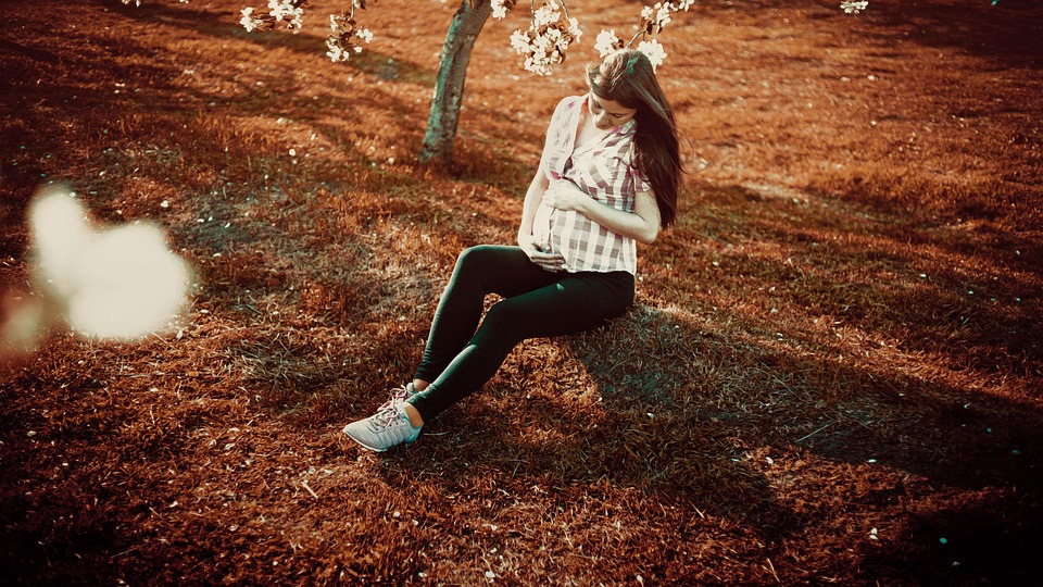 Pregnant women is seating at the grass ans she is wearing the best maternity leggings