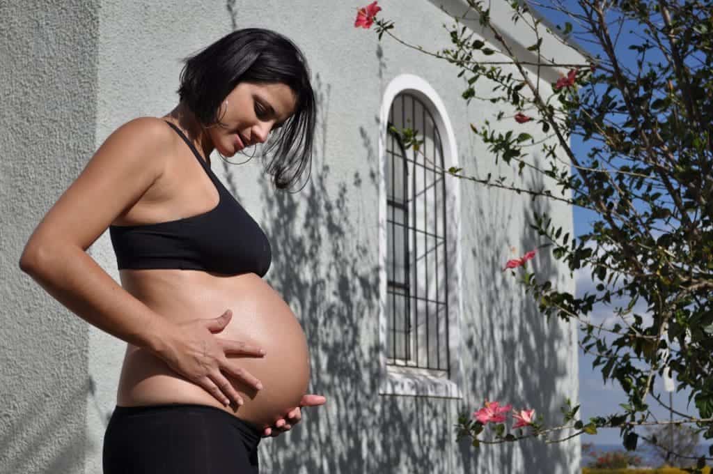 Pregnant women is wearing a maternity bra while standing outside her house