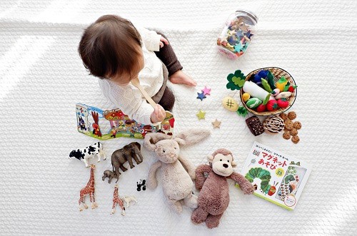 baby sitting on the white cloth with the toys