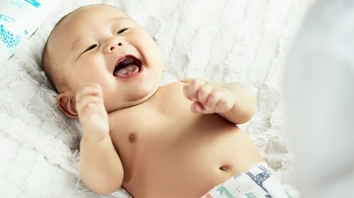 topless baby lying on bed