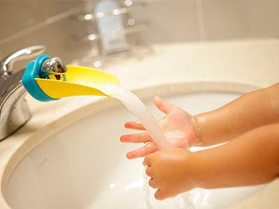 toddler washing his hands qith aqueduck faucet extender