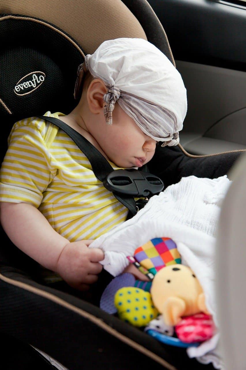 Baby boy is sleeping while seating at the car seat