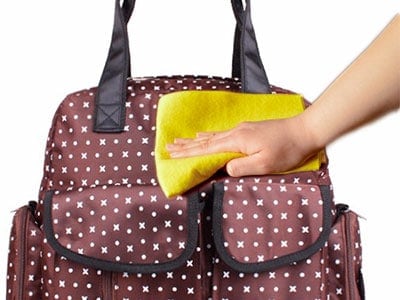 wiping down a dirty diaper bag with a cloth