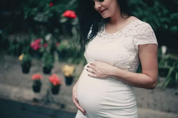Woman in white dress holding her stomach
