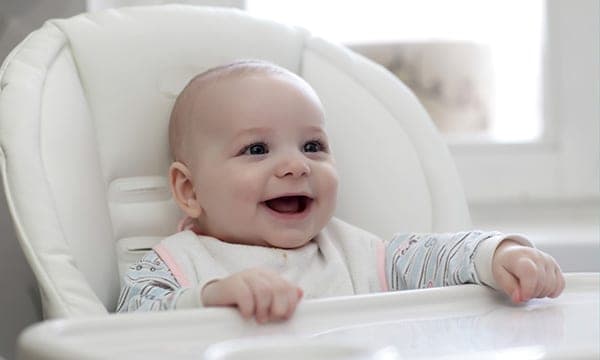 baby smiling while sitting in a high chair