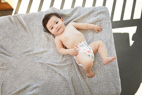 baby in a diaper on a gray bed