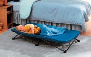 kid sleeping on a portable toddler bed beside an adult bed