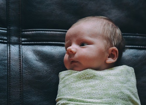 baby covered green blanket