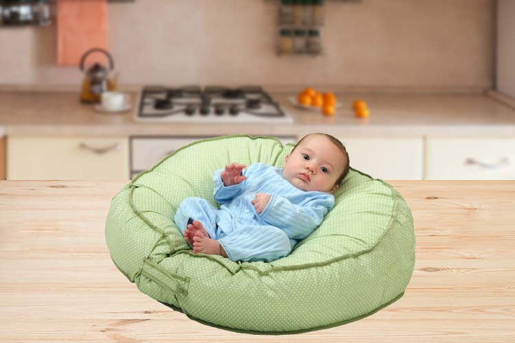 Baby laying on infant lounger in kitchen