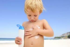 cute child applying sunscreen at the beach