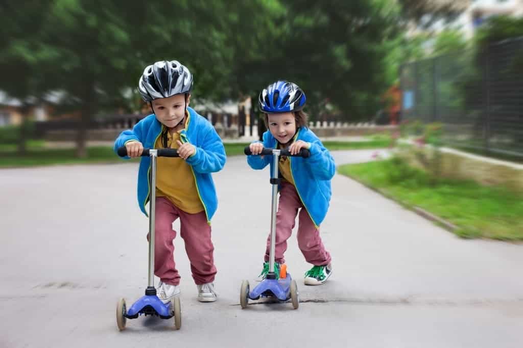 Two boys riding scooters