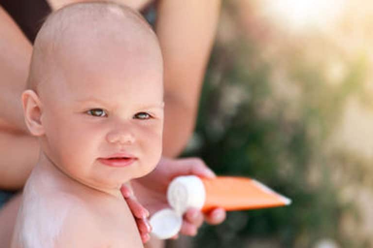 applying sunscreen to a baby