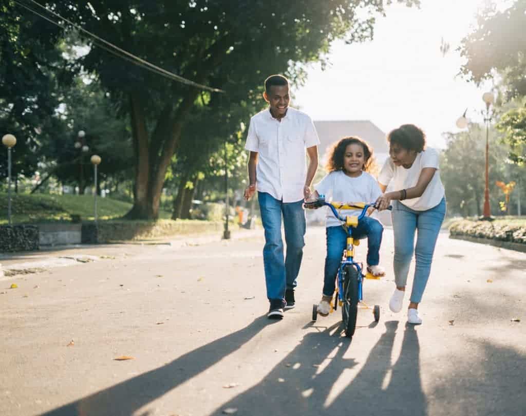 parents teaching their child on how to ride a bike